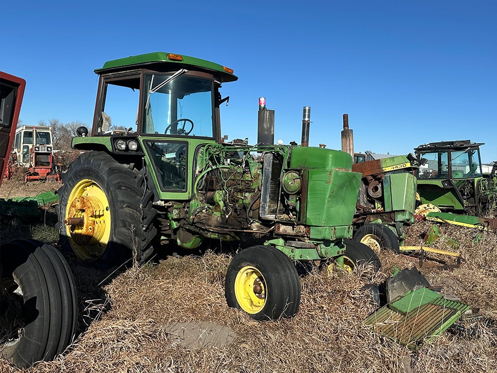 Salvaged tractor in a row with their engine cover parts on the ground