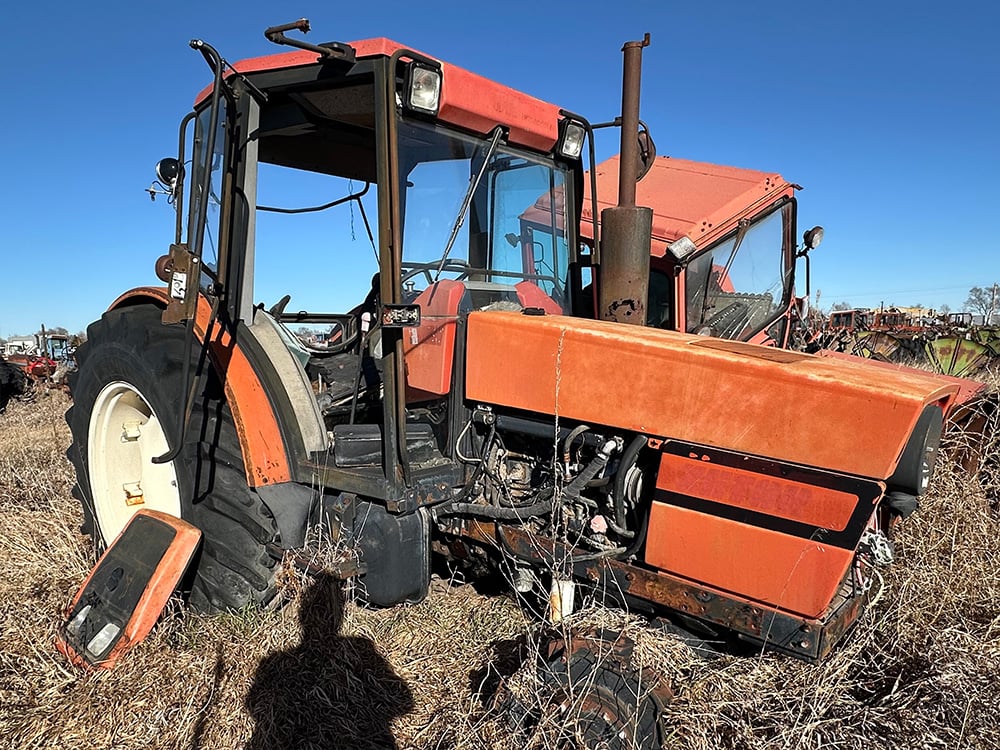 Red salvaged tractor with no front wheel