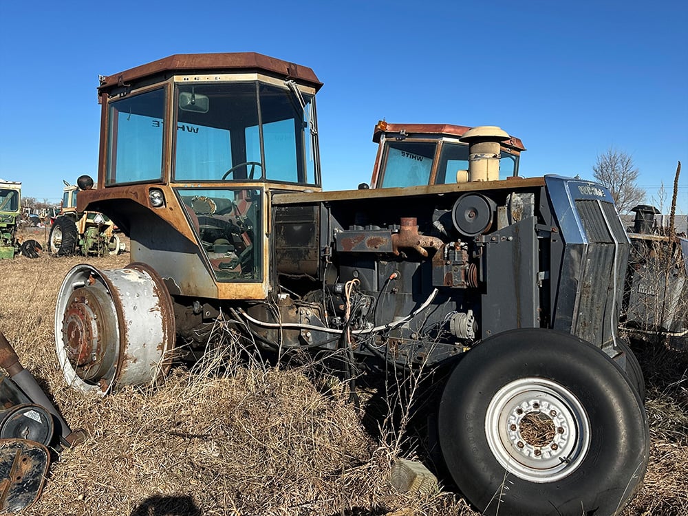 Salvaged brown tractor missing back wheel and engine cover side