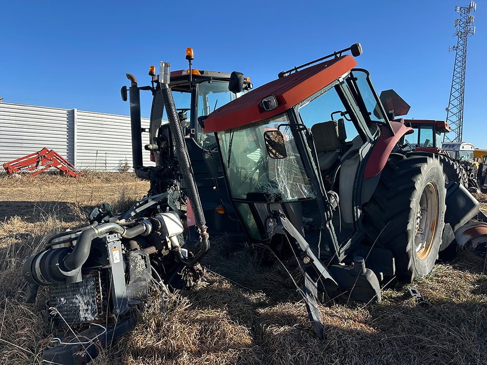 Two broken down red tractor, one with broken wind sheidl and both missing front tires