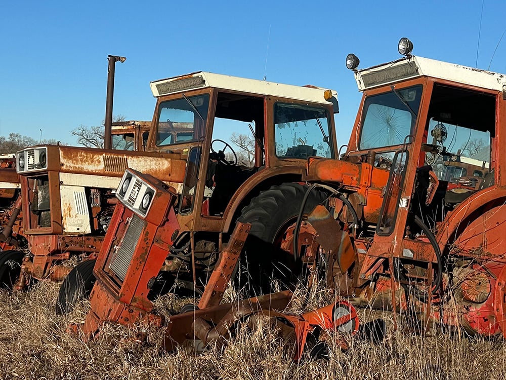 white and orange tractors in a row, one having tire rings next to it