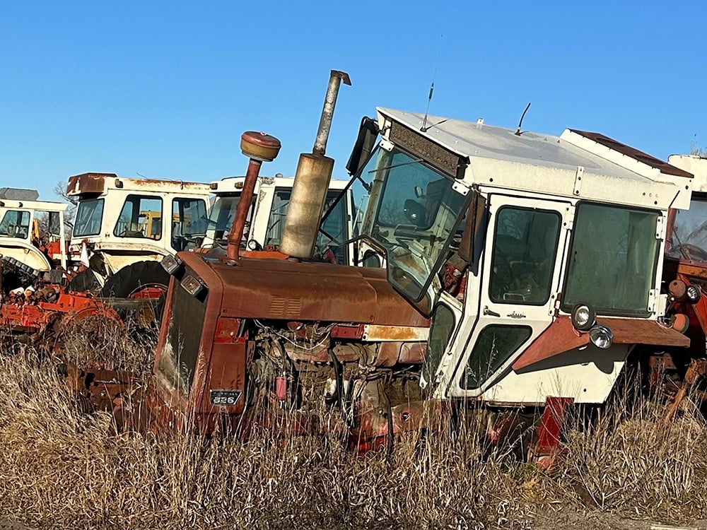 Broken down white and orange tracotors in a row