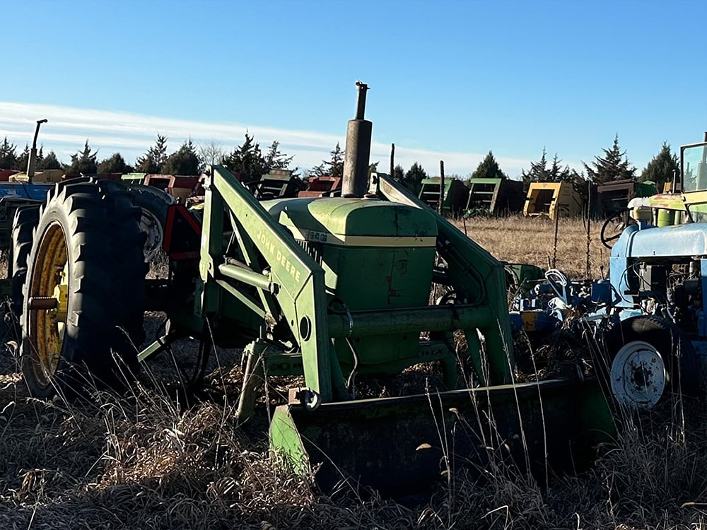 Salvaged international compact tractor next to broken blue compact tractor