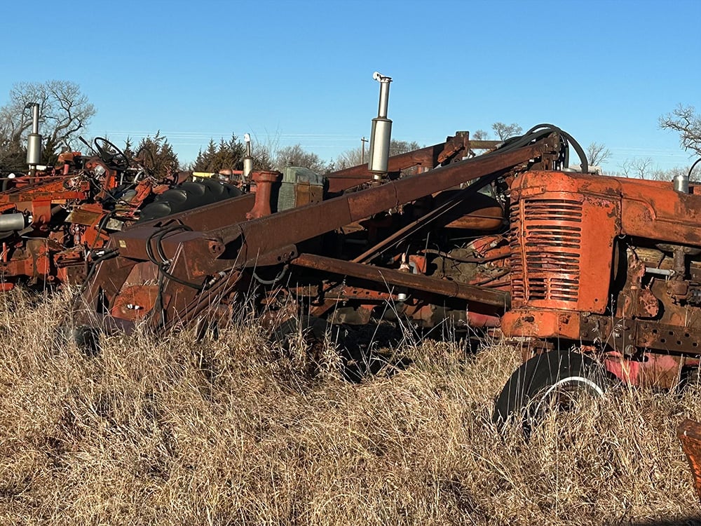 Salvaged orange tractors in a row show casing their various attachments