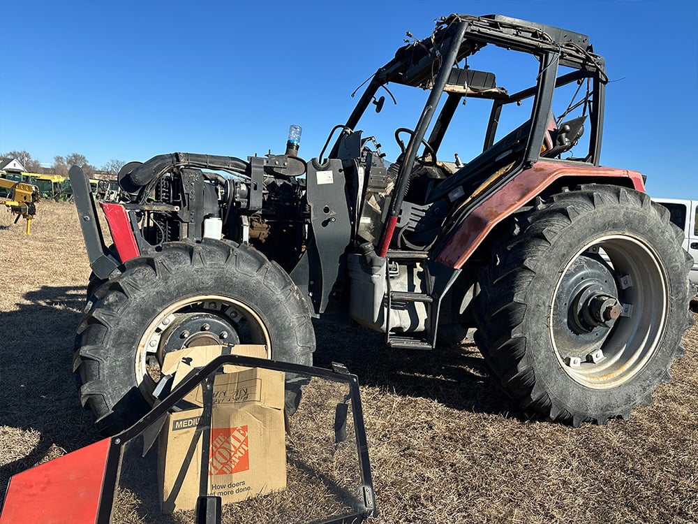 Red salvaged tractor with no cover on engine