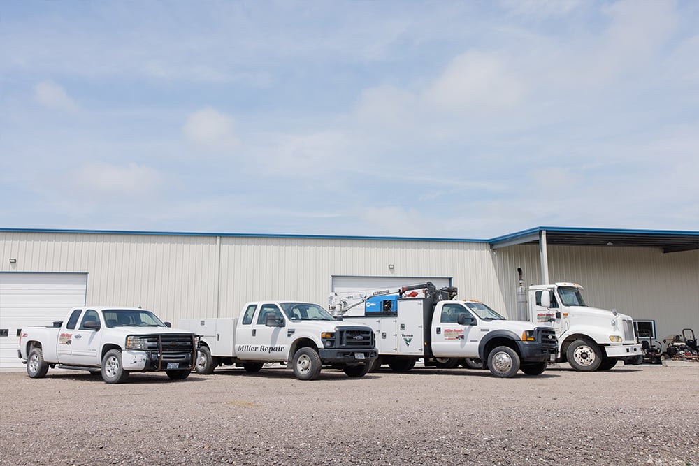 Four Miller service trucks parked outside of our building